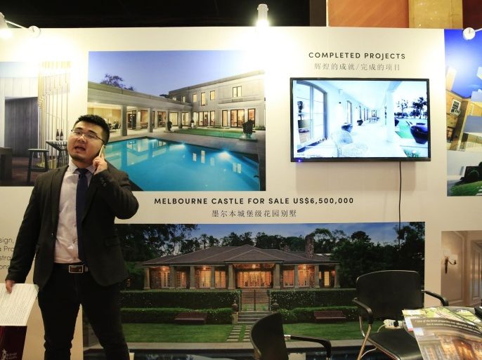 A visitor speaks on a phone in front of a booth, exhibiting photos of luxury properties in Melbourne, during the Luxury Property Showcase (LPS) Beijing 2016 event at a hotel in Beijing, China, 22 April 2016. Hundreds of visitors attended on the first day of the LPS Beijing 2016, an event showcasing luxury properties from more than 35 countries including Australia, Canada, Spain, Uruguay, and the United States among others. Interest in overseas property remain high among