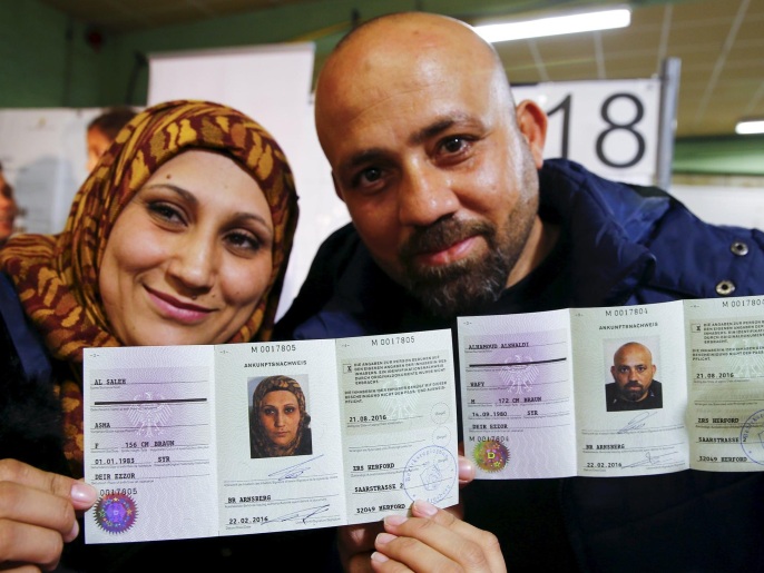 لاجئان سوريان يستعرضان بطاقة التسجيل التي منحتها لهم السلطات الألمانية (غيتي/رويترز) 