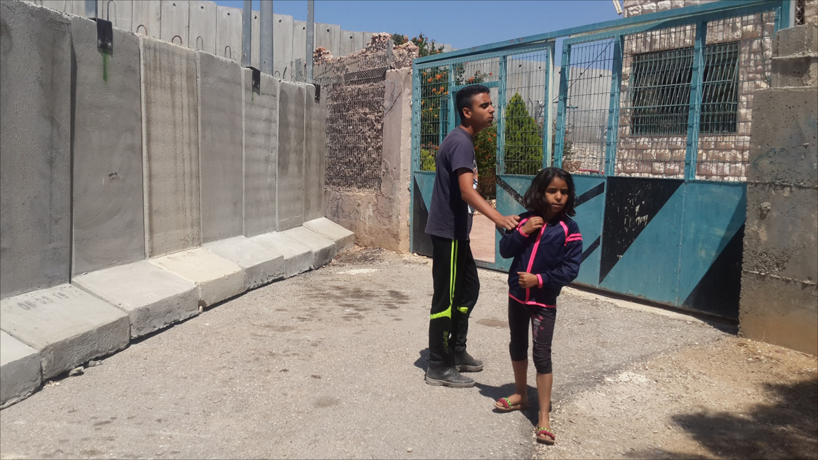 ‪‬ جدران إسرائيلية عازلة تصل مداخل المنازل في قرية حزما شمال شرق القدس(الجزيرة)