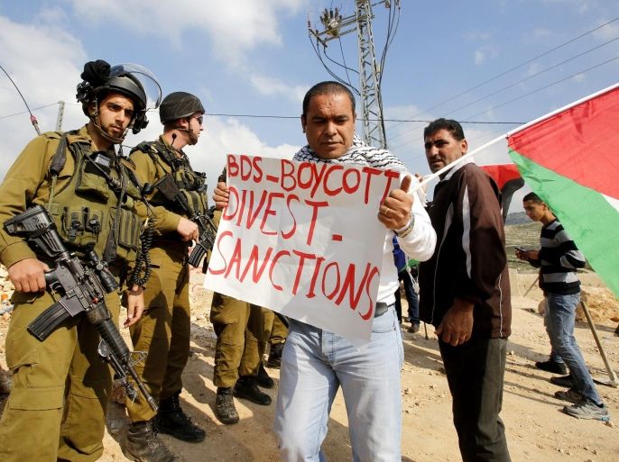 Israeli Border Police and army soldiers block Palestinian protesters from advancing near the southern West Bank village of Jab'a, 14 March 2015. The protesters carried posters referring to the BDS (Boycott, Divestment and Sanctions) movement which aims to put pressure on Israel to end its engagement in the Palestinian territories.