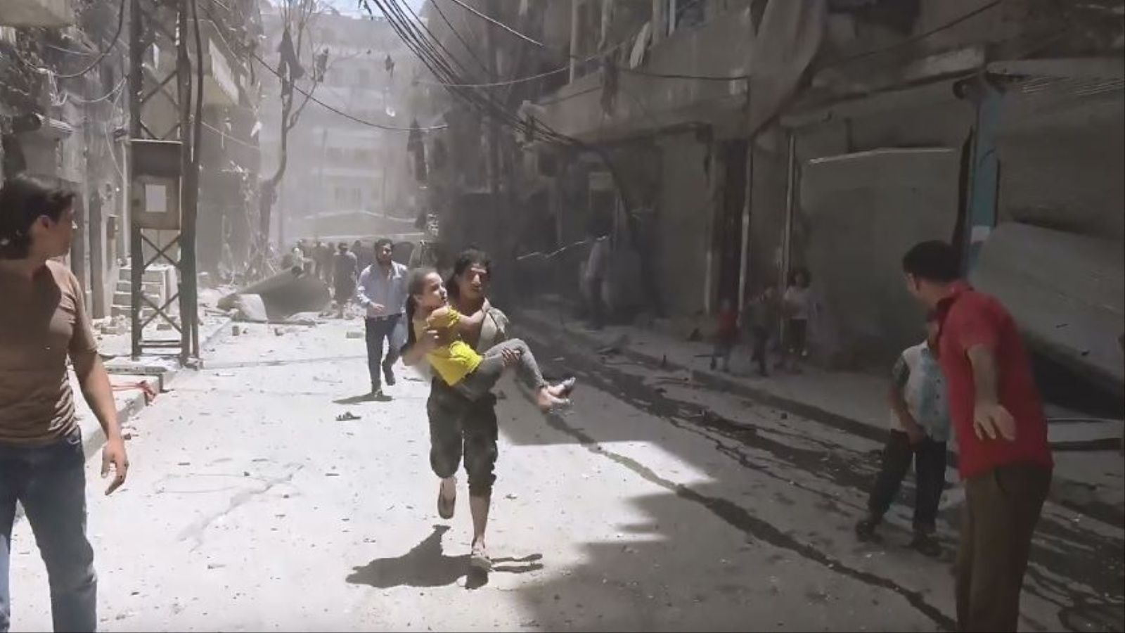 ‪سوري ينقل فتاة إلى سيارة إسعاف بعد إصابتها في غارات اليوم على حلب‬ (ناشطون)