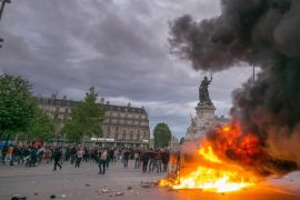 Protesters stand next to a car that was set on fire at Place de la Republique square in Paris, France, 14 June 2016. Labor unions demonstrated during a national strike across France to protest against about employment law reforms in the so-called El Khomri bill.