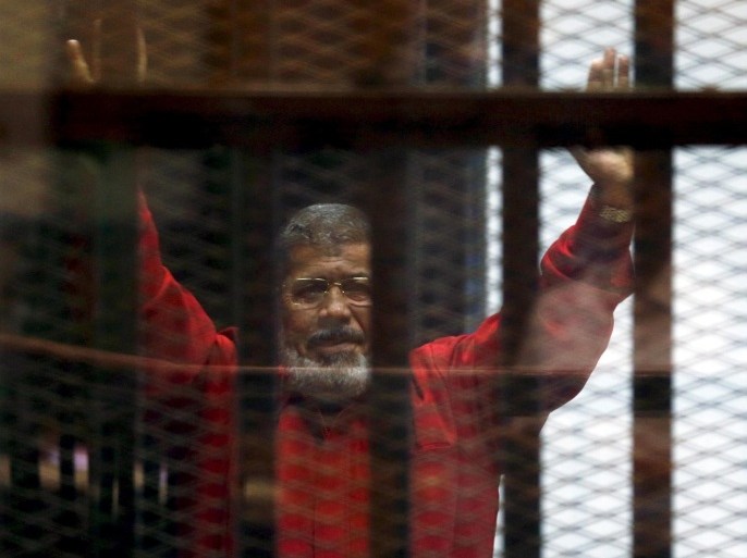 FILE PHOTO: Deposed President Mohamed Mursi greets his lawyers and people from behind bars at a court wearing the red uniform of a prisoner sentenced to death, during his court appearance with Muslim Brotherhood members on the outskirts of Cairo, Egypt, June 21, 2015. REUTERS/Amr Abdallah Dalsh/File photo