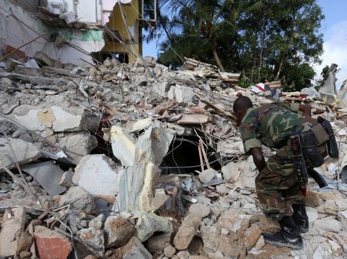 A Somali government soldier inspects the debris at the scene of a suicide bomb attack outside Nasahablood hotel in Somalia's capital Mogadishu, June 26, 2016. REUTERS/Feisal Omar