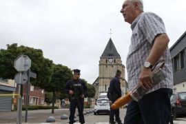 A man walks past French CRS police who stand guard in front of the church a day after a hostage-taking in Saint-Etienne-du-Rouvray near Rouen in Normandy, France, where French priest, Father Jacques Hamel, was killed with a knife and another hostage seriously wounded in an attack on the church that was carried out by assailants linked to Islamic State, July 27, 2016. REUTERS/Pascal Rossignol - ATTENTION EDITORS FRENCH LAW REQUIRES THAT VEHICLE REGISTRATION PLATES ARE
