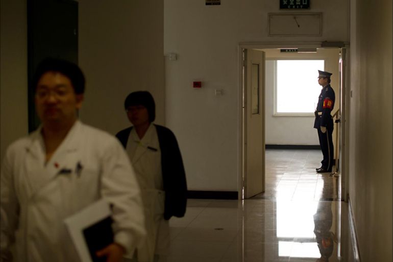 مرور طبيب صيني بينما يظهر حارس أمن على باب أحد الممرات في مستشفى بكين المركزي