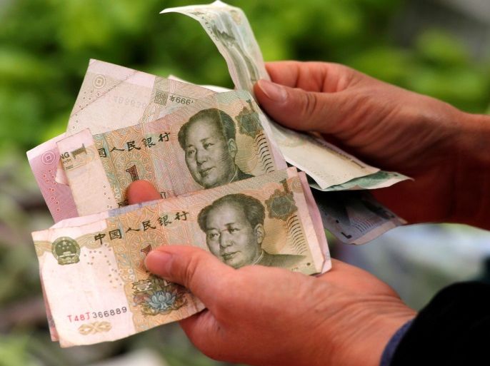 A customer counts Chinese Yuan banknotes as she purchases vegetables at a market in Beijing, China, May 9, 2016. REUTERS/Kim Kyung-Hoon/File Photo