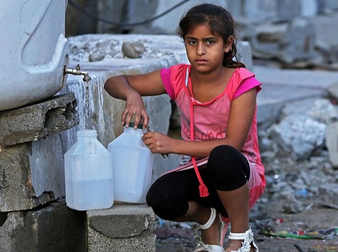 A Palestinian girl fills plastic bottles with drinking water in the early morning, in Al-Sheiaeiya neigbourhood in the east of Gaza City on 14 September 2014. The school year started Sunday in the Gaza Strip after a two-week delay due to destruction caused by 50 days of Israeli-Palestinian fighting that ended on August 26.