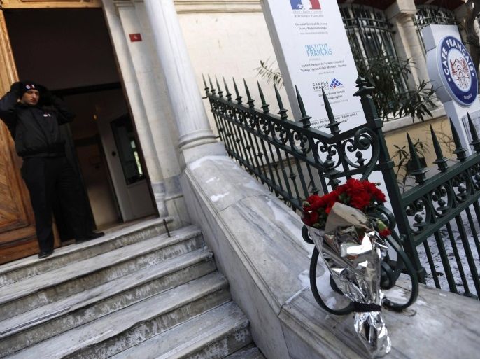 A private security employee stands as red carnations are placed outside the Consulate General of France to remember the victims of an attack in Paris, in Istanbul January 8, 2015. French police extended a manhunt on Thursday for two brothers suspected of killing 12 people at a satirical magazine in Paris in a presumed Islamist militant strike that national leaders and allied states described as an assault on democracy. France began a day of mourning for the journalists and police officers shot dead on Wednesday morning by black-hooded gunmen using Kalashnikov assault rifles. French tricolour flags flew at half mast throughout the country. REUTERS/Murad Sezer (TURKEY - Tags: CRIME LAW CIVIL UNREST POLITICS)