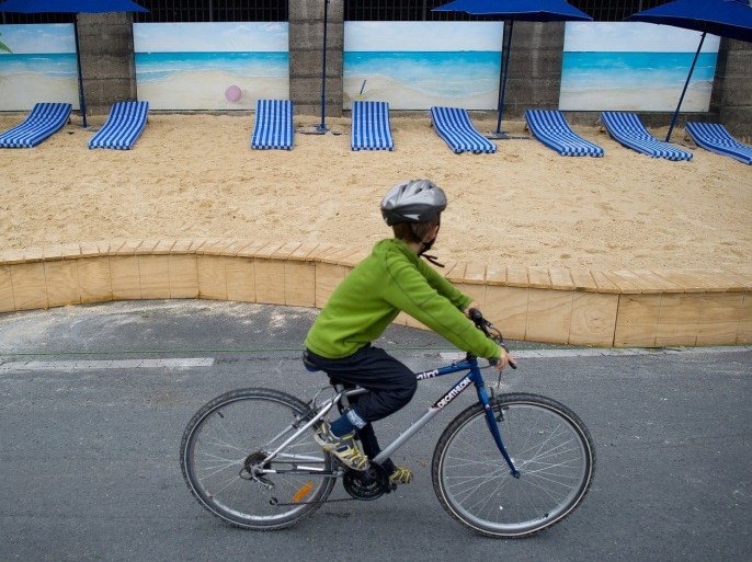 A child rides his bike along the River Seine on July 21, 2011 in Paris, on the opening day of the Paris Plage yearly event. For the tenth summer, Paris transforms the banks of the Seine into full-fledged beaches with palm trees, outdoor showers and hammocks. The event runs until August 21, 2011.