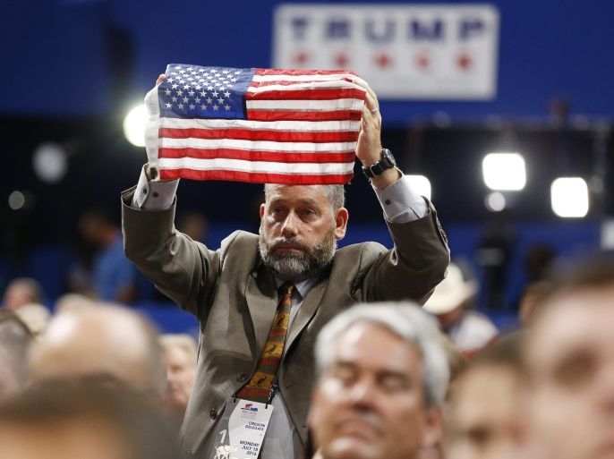 A delegate holds an American flag as John Teigen and Mark Geist talk about the Benghazi attack during the second session on the first day of the 2016 Republican National Convention at Quicken Loans Arena in Cleveland, Ohio, USA, 18 July 2016. The four-day convention is expected to end with Donald Trump formally accepting the nomination of the Republican Party as their presidential candidate in the 2016 election.