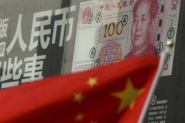 China's national flag is seen in front of a poster explaining the design of new 100 yuan banknote at a branch of a commercial bank at a business district in Beijing, China, in this January 21, 2016 file picture. China plans to target broad-based money supply growth of around 13 percent this year, sources said, a signal that further monetary policy easing is likely during a painful economic restructuring that could see millions of workers losing jobs. REUTERS/Kim Kyung-