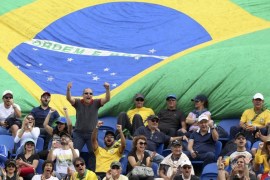 2016 Rio Olympics - Tennis - Preliminary - Men's Singles Third Round - Olympic Tennis Centre - Rio de Janeiro, Brazil - 11/08/2016. Fans react in front of a large Brazilian national flag during a match between Thomaz Bellucci (BRA) of Brazil and David Goffin (BEL) of Belgium. REUTERS/Kevin Lamarque FOR EDITORIAL USE ONLY. NOT FOR SALE FOR MARKETING OR ADVERTISING CAMPAIGNS.
