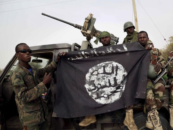FILE PHOTO - Nigerian soldiers hold up a Boko Haram flag that they had seized in the recently retaken town of Damasak, Nigeria, March 18, 2015. REUTERS/Emmanuel Braun/File Photo