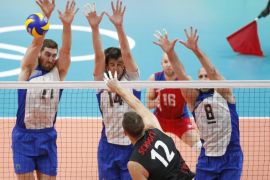 Gavin Schmitt (B) of Canada in action against Maxim MikHaylov (L), Artem Volvich (C) and Sergey Tetyukhin (R) of Russia during their men's quarterfinal volleyball match of the Rio 2016 Olympic Games at Maracanazinho indoor arena in Rio de Janeiro, Brazil, 17 August 2016.