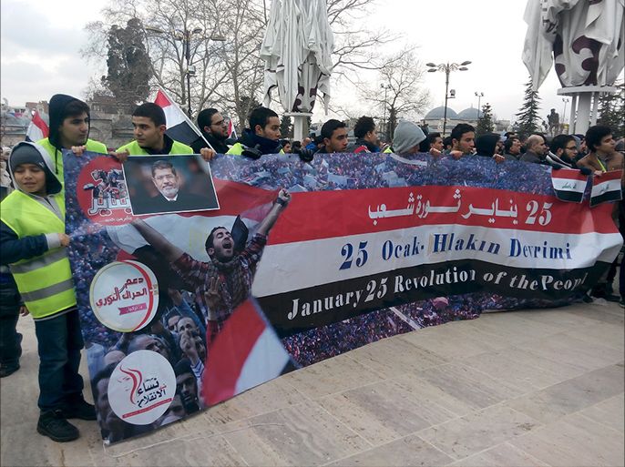 شبان مصريون يرفعون لافتة داعمة للشرعية في ساحة جامع الفاتح باسطنبول في ذكرى ثورة 25 يناير