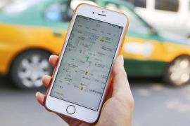 (FILE) A file picture dated 13 May 2016 shows a commuter handling an iPhone displaying the Didi Chuxing app at a street in Beijing, China. According to media reports on 01 August 2016, quoting unnamed sources acquainted with the deal, Didi Chuxing is planning to buy its local rival Uber China. The merger deal, which will end bruising competition between the two transportation network businesses, is reported to be valued at 35 billion US dollar in the combined company. D