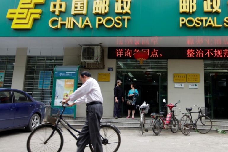 A man pushes his bicycle past a branch of China Post's Postal Savings Bank of China in Wuhan, Hubei province May 4, 2012. REUTERS/Stringer/File Photo CHINA OUT. NO COMMERCIAL OR EDITORIAL SALES IN CHINA