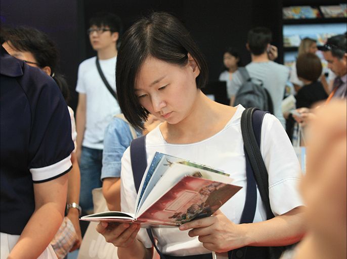 فتاة صينية تتصفح كتاباً في معرض بكين الدولي للكتاب