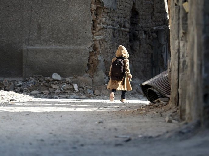A child carries a school bag near damaged buildings in Harasta, in the eastern Damascus suburb of Ghouta, Syria January 30, 2016. REUTERS/Bassam Khabieh