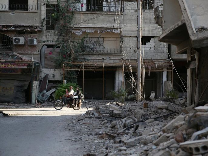 People ride a motorcycle near damaged buildings in rebel-held Ain Tarma, eastern Damascus suburb of Ghouta, Syria September 17, 2016. Picture taken September 17, 2016. REUTERS/Bassam Khabieh