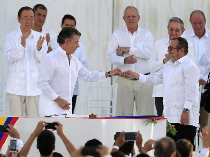 Colombian President Juan Manuel Santos (C-L) hands over a pin with the image of the dove of peace to Chief of Revolutionary Armed Forces of Colombia (FARC) Rodrigo Londono Echeverri (C-R), alias 'Timochenko', after the signing the peace agreement between Colombia's government and FARC to end over 50 years of conflict, in Cartagena, Colombia, 26 September 2016. The pact is the result of nearly four years of talks in Havana and was signed at a solemn ceremony in Cartag