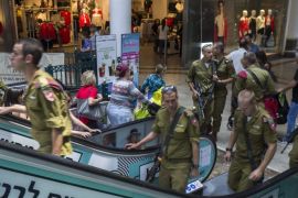 Israeli infantry soldiers with automatic assault weapons as they visit a main Jerusalem shopping mall, 24 July 2016. Israelis are used to seeing armed soldiers and civilians carrying weapons as they carry on with everyday events such as shopping or going to cafes. Everyone entering a shopping mall in Israel must open bags or inspection and through a metal detector.
