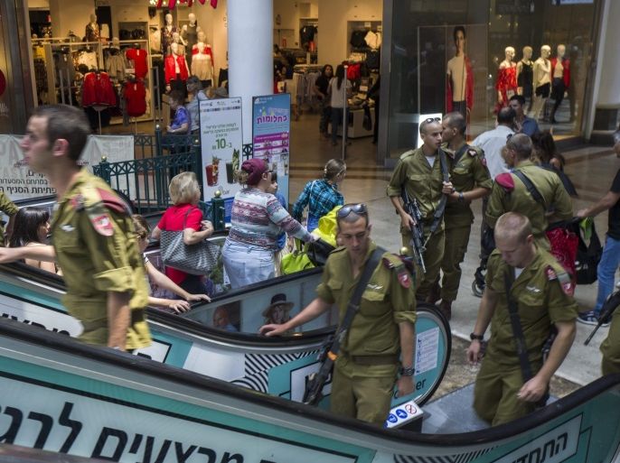 Israeli infantry soldiers with automatic assault weapons as they visit a main Jerusalem shopping mall, 24 July 2016. Israelis are used to seeing armed soldiers and civilians carrying weapons as they carry on with everyday events such as shopping or going to cafes. Everyone entering a shopping mall in Israel must open bags or inspection and through a metal detector.