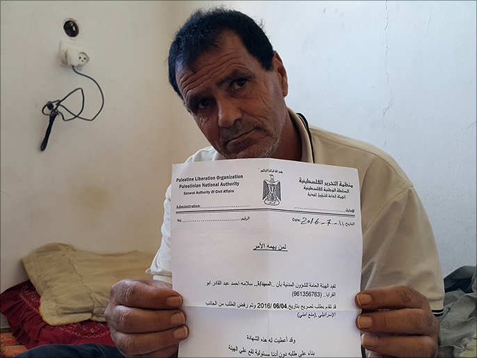 ‪أبو القرايا يحمل صورة عن رفض الاحتلال السماح له بالعودة لزوجته وأبنائه بالضفة‬ (الجزيرة)