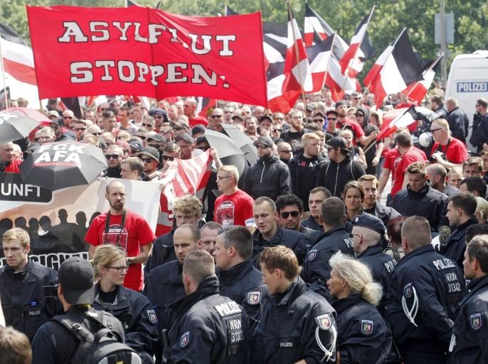 Demonstrators carry a banner that reads 'Stop the asylum flood' as they are accompanied by riot police during a right-wing extremist rally in Dortmund, Germany, 04 June 2016. Some 2,500 people have gathered for the protest march, with another 2,500 left-wing radicals on the move in the city.