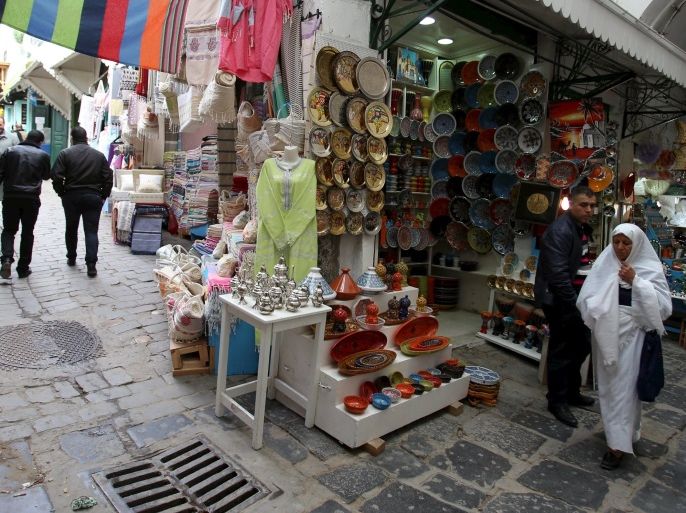 Tunisians walk near at a souvenir shop in the medina, the old city of Tunis, Tunisia, February 16, 2016. An International Monetary Fund team visits Tunisia this week to negotiate a new credit line for a government hit by collapsing tourism revenues, unemployment, militancy and social unrest. Picture taken February 16, 2016. REUTERS/Zoubeir Souissi