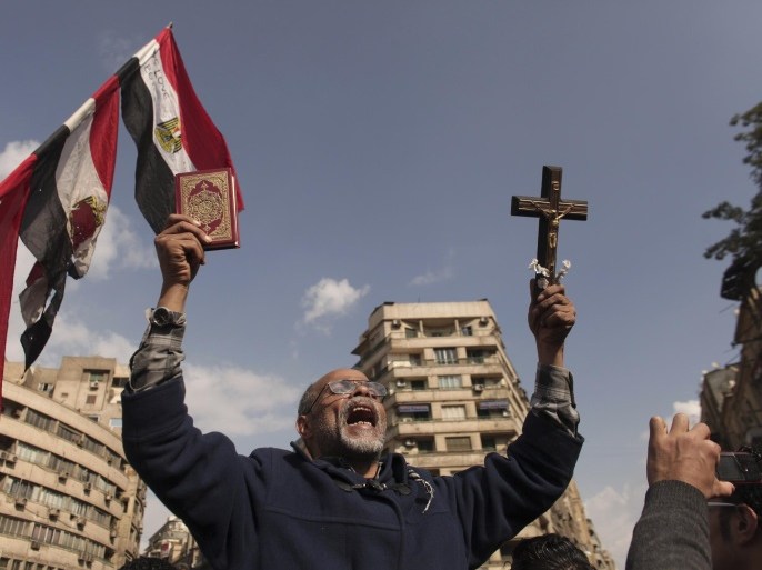 An Egyptian protester chants slogans while holding a cross and a Quran in Tahrir Square, Friday, Nov. 23, 2012. Supporters and opponents of Egypt's Islamist President Mohammed Morsi staged rival rallies Friday after he assumed sweeping new powers, a clear show of the deepening polarization plaguing the country. In a Thursday Nov. 22, 2012 decree Morsi put himself above the judiciary and also exempted the Islamist-dominated constituent assembly writing Egypt's new constitution from judicial review.