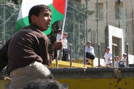 طفل فلسطني يحمل العلم الفلسطيني أمام مجموعة من المتدينين المتطرفين خلال اعتصام في البلدة القديمة بالخليل