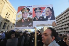 A supporter of Egypt's army chief General Abdel Fatah al-Sisi holds a poster of al-Sisi and former Egypt president Gamal Abdel Nasser, in front of the damaged buildings of the Cairo Security Directorate (R), which includes police and state security, and Museum of Islamic Art building, after a bomb attack in downtown Cairo, January 24, 2014. A suicide bomber in a car blew himself up in the parking lot of a top security compound in central Cairo on Friday, killing at least four people in one of the most high-profile attacks on the state in months, security sources said. The poster reads " We will die and Egypt will live. Egypt is with you." REUTERS/Amr Abdallah Dalsh (EGYPT - Tags: POLITICS CRIME LAW CIVIL UNREST)