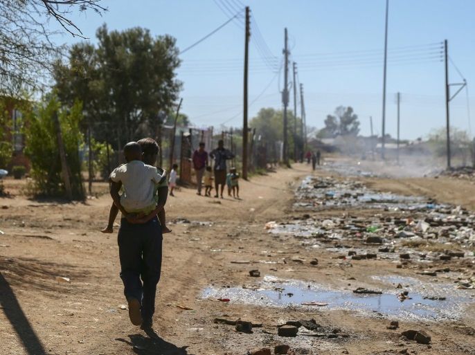 (04/20) A South African woman carries a child down a polluted street in Kimberley, South Africa, 30 September 2012. The world's best skateboarders competed in Kimberley for the biggest cash prize in skateboarding during the World Championships of Skateboarding Maloof Money Cup between 28-30 September 2012. The Maloof Money Cup South Africa skate park is built next to the famous Kimberley diamond mine and is a new destination for skateboarders around the world as well as being a centre for youth development and community upliftment through the skate for hope programme initiated by the US hotel property tycoons the Maloof brothers. EPA/NIC BOTHMA PLEASE REFER TO ADVISORY NOTICE epa03459533 FOR FULL FEATURE TEXT