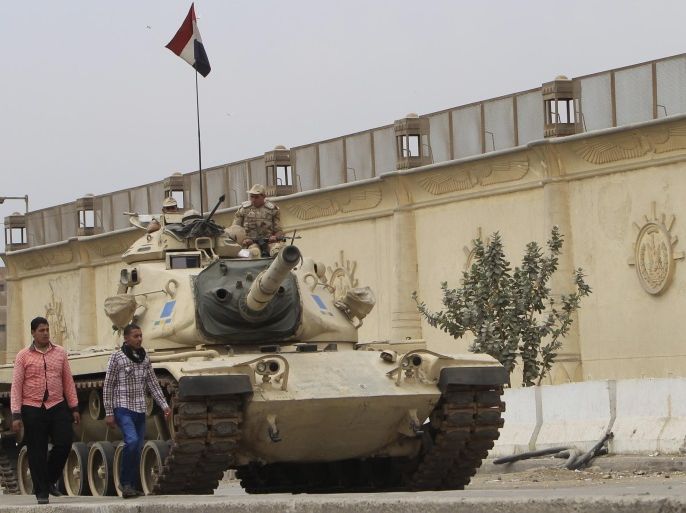 People walk past an Egyptian army tank positioned outside Cairo's Tora prison, March 23, 2014. REUTERS/Mohamed Abd El Ghany