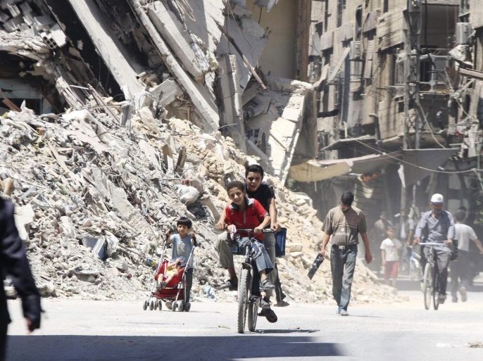 Boys ride a bicycle past other civilians near damaged buildings in the Damascus suburb of Harasta August 24, 2014. Picture taken August 24, 2014. REUTERS/Badra Mamet (SYRIA - Tags: POLITICS CIVIL UNREST CONFLICT TPX IMAGES OF THE DAY SOCIETY TRANSPORT)