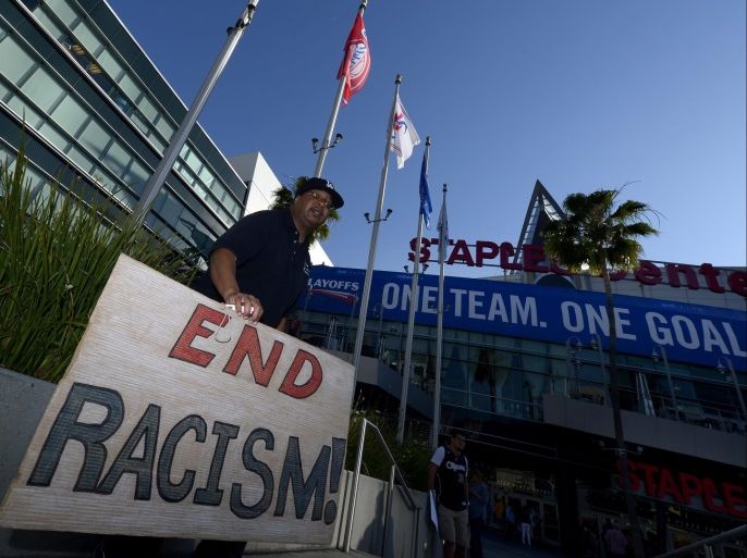A fan holds a banner reading 'End Racism!' as he stands outside Staples Center prior to the Golden State Warriors at Los Angeles Clippers NBA Conference Quarterfinal game five playoff in Los Angeles, California, USA, 29 April 2014. Clippers owner Donald Sterling was banned for life and fined 2.5 million US dollar for racist comments he made to girlfriend who was audio taping the conversation. EPA/PAUL BUCK CORBIS OUT
