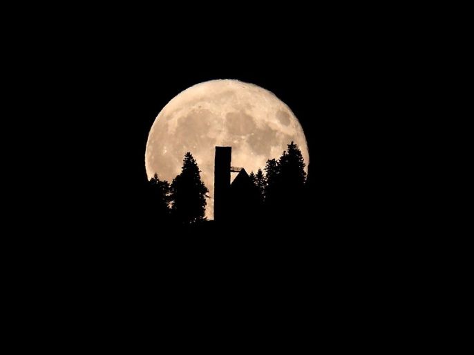 The full moon rises behind the St Georg Church on the 1055 m high Auerberg mountain in Stoetten, Germany, 16 October 2016.
