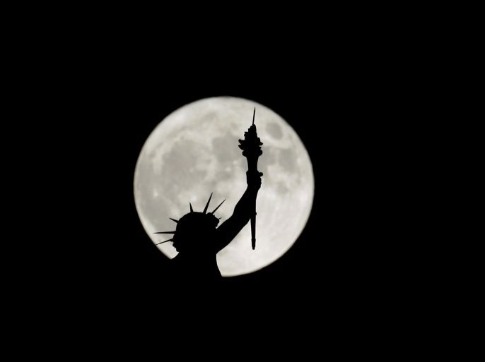 The rising supermoon is seen behind a statue on top of the Natural History Museum in Vienna, Austria November 14, 2016. REUTERS/Leonhard Foeger