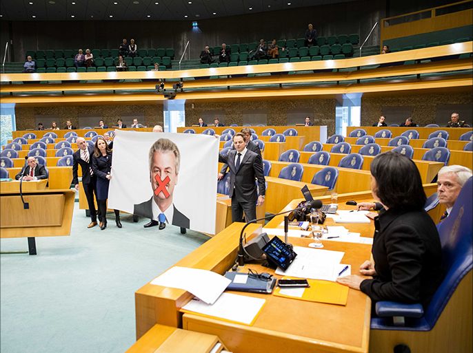 epa05634955 Party for Freedom (PVV) members hold a poster depicting party leader Geert Wilders with a red cross over his mouth, as they protest in the Senate (Tweede Kamer) at the Binnenhof in The Hague, The Netherlands, 17 November 2016. According to reports, Wilders is facing charges for allegedly inciting hatred against the Dutch Moroccan minority. EPA/BART MAAT