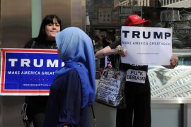 A woman wearing a Muslim headscarf walks past people holding U.S. Republican presidential nominee Donald Trump signs before the annual Muslim Day Parade in the Manhattan borough of New York City, September 25, 2016. REUTERS/Stephanie Keith/File Photo