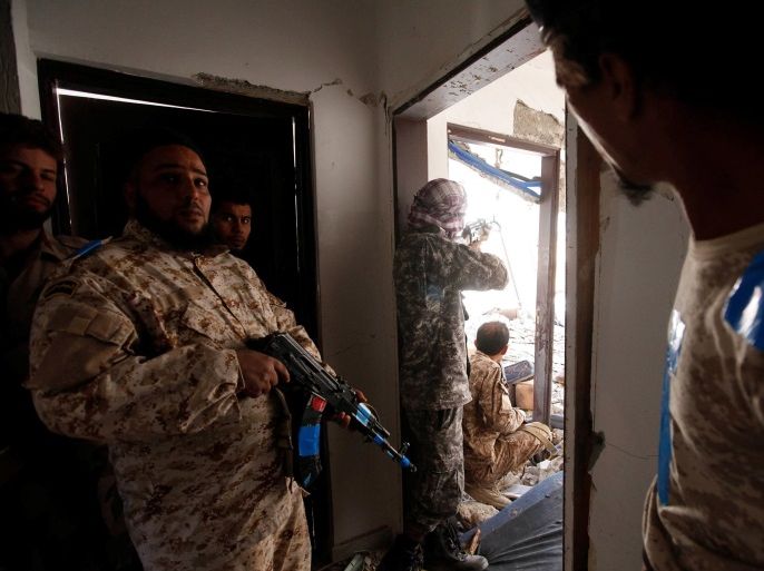 A fighter of Libyan forces allied with the U.N.-backed government aims his weapon as others take cover inside a house at the front line of fighting with Islamic State militants in Ghiza Bahriya district in Sirte, Libya November 9, 2016. Picture taken November 9, 2016. To match Insight LIBYA-SECURITY/ REUTERS/Ismail Zitouny