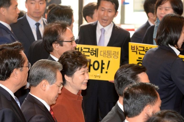 South Korean President Prak Geun-hye (in red) walks past members of the minor opposition Justice Party at the National Assembly in Seoul, South Korea, November 8, 2016. The placards read: "Step down President Park Geun-hye". Yonhap/Bae Jae-man/via REUTERS ATTENTION EDITORS - THIS IMAGE HAS BEEN SUPPLIED BY A THIRD PARTY. SOUTH KOREA OUT. FOR EDITORIAL USE ONLY. NO RESALES. NO ARCHIVE.