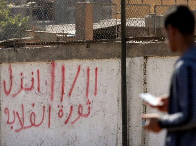 A man walks and speaks in his mobile in front of a wall with graffiti in support of the Ghalaba Movement, asking Egyptians to participate in demonstrations against the Egyptian regime on November 11, in Cairo, Egypt November 9, 2016. The words read "11/11 Revolutions of Ghalaba (Marginalised)". REUTERS/Amr Abdallah Dalsh