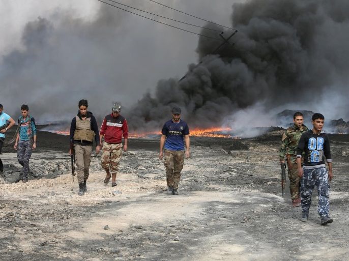Tribal fighters walk as fire and smoke rises from oil wells, set ablaze by Islamic State militants before IS militants fled the oil-producing region of Qayyara, Iraq, November 1, 2016. REUTERS/Alaa Al-Marjani TPX IMAGES OF THE DAY