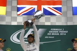 Formula One - F1 - Brazilian Grand Prix - Circuit of Interlagos, Sao Paulo, Brazil - 13/11/2016 - Mercedes' Lewis Hamilton of Britain raises his trophy during the victory ceremony after winning the race as second placed finisher and teammate Nico Rosberg of Germany (L) and third placed finisher Red Bull's Max Verstappen of the Netherlands look on. REUTERS/Nacho Doce