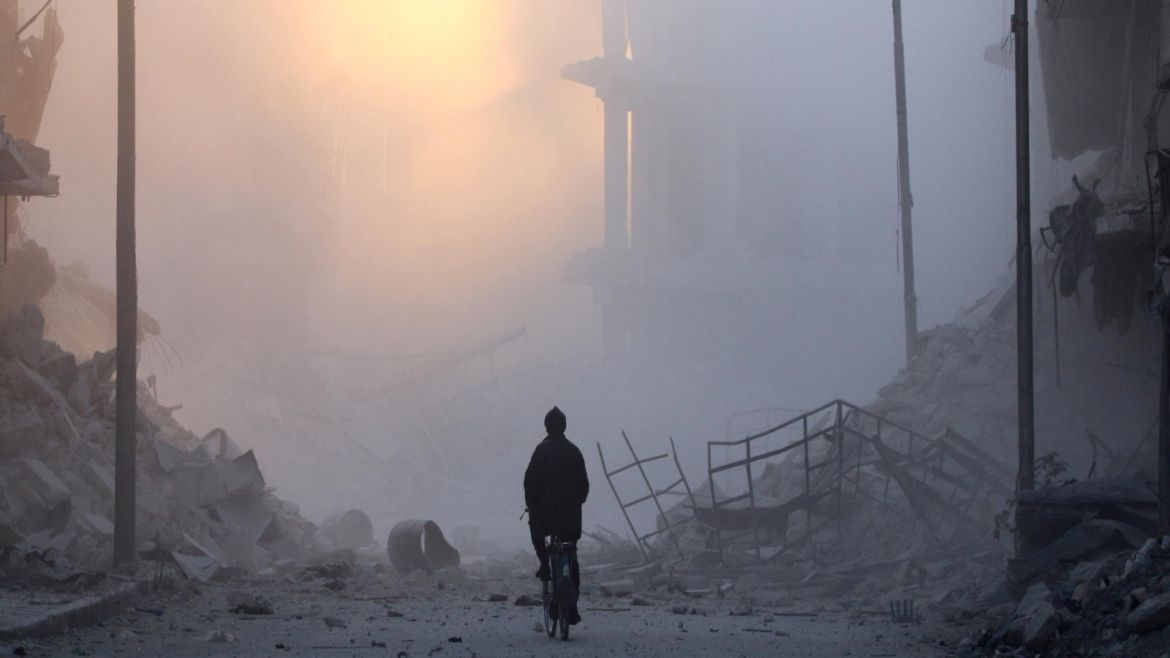 A man rides a bicycle amidst dust near rubble of damaged buildings after a strike on the rebel held besieged al-Shaar neighbourhood of Aleppo, Syria, November 26, 2016. REUTERS/Abdalrhman Ismail