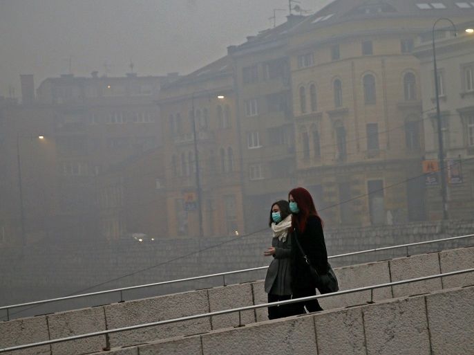 Women wearing masks walk as smog blankets Sarajevo, Bosnia and Herzegovina December 23, 2015. With severe air pollution affecting the city nestled among the mountains, the authorities have declared the first level of preparedness, advising the segment of the population that is at health risk to reduce movement in the mornings and evenings, appealing to drivers to use motor vehicles less and ordering heating utilities to lower the emission of harmful gases. REUTERS/Dado