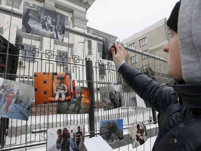 ‪محتجون يعلقون صور الانتهاكات في حلب على أسوار سفارة روسيا في كييف‬ (رويترز)